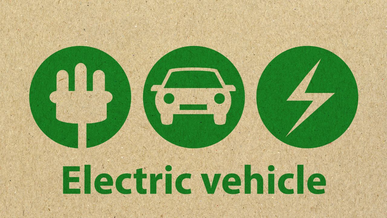 Infografica su sfondo di cartone riciclato con tre icone verdi (spina elettrica, auto, fulmine) e la scritta Electric Vehicle, simbolo di trasporto ecologico.